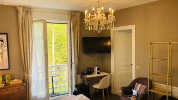A hotel room with a bed, a desk, a chair, a TV, and a balcony with curtains.