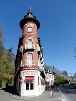 Un hotel de ladrillo rojo con una torre, balcones y un letrero que dice "HOTEL RESTAURANT Le Roc au Chien".