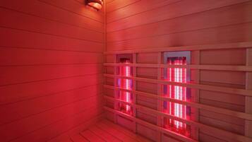 A sauna room with wooden walls and benches, featuring a red light.