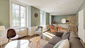 Un salon moderne comprenant un canapé, des fauteuils, une table et un coin repas avec une chaise et une petite table.