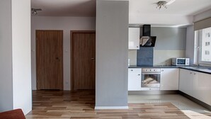 Une cuisine moderne équipée d’un four à micro-ondes, d’un four traditionnel et de placards. Elle comprend deux portes en bois et une fenêtre avec vue.