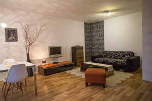 Un salon moderne comprenant un canapé, un téléviseur et un coin repas avec des chaises et une table.