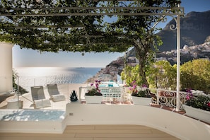 Una terraza con piscina, tumbonas y plantas en macetas.