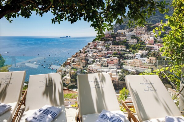 Blick auf das Meer von einer Villa mit Liegestühlen, mit der Aufschrift "Villa Fiorentino" und "Infinity Pool & SPA".