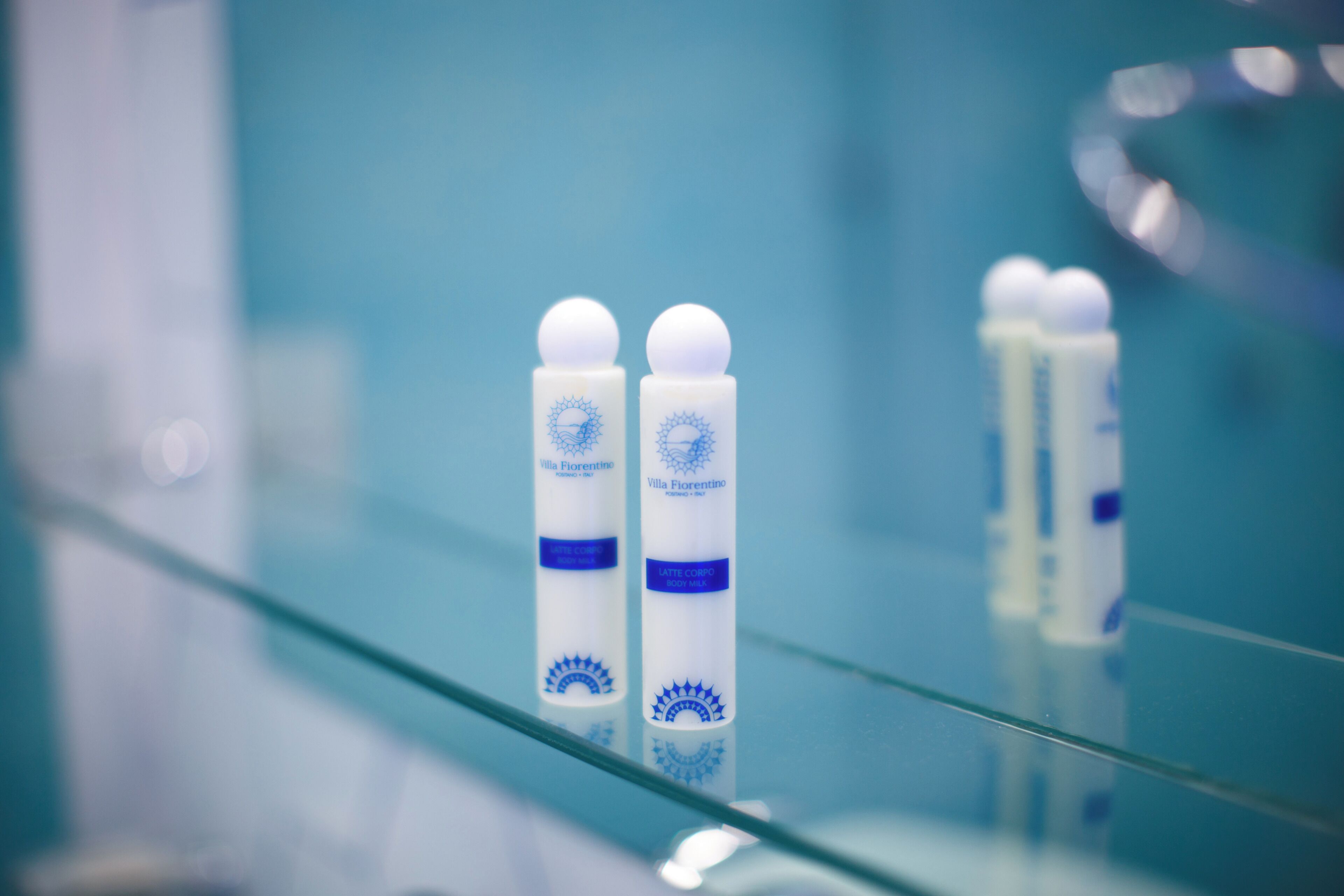 Two bottles of Villa Fiorentino body milk on a glass shelf.