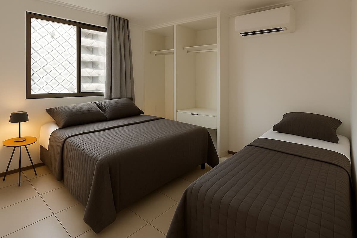 A bedroom with two beds, a wardrobe, a bedside table with a lamp, and a window with curtains.