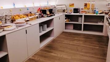Una cucina moderna con mobili bianchi, pavimento in legno e diversi cibi esposti sul bancone.