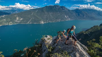 Two hikers on a rocky outcrop with a mountainous backdrop and a lake.