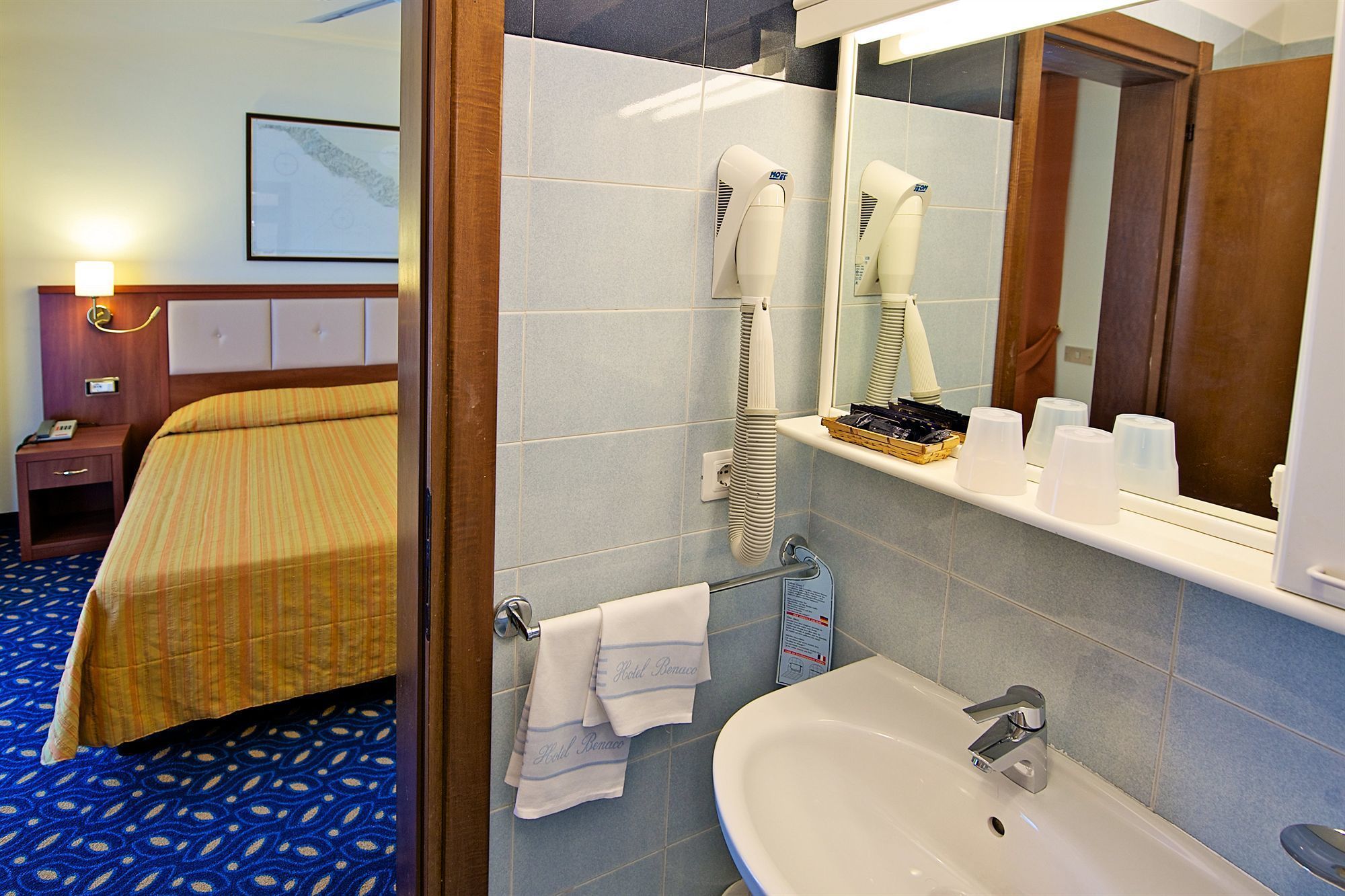 A hotel room with a bed, a bathroom with a sink, and a mirror.
