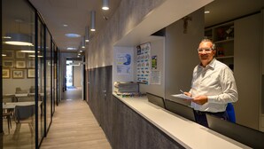 A modern reception area with a glass partition, a reception desk, and a corridor with seating.