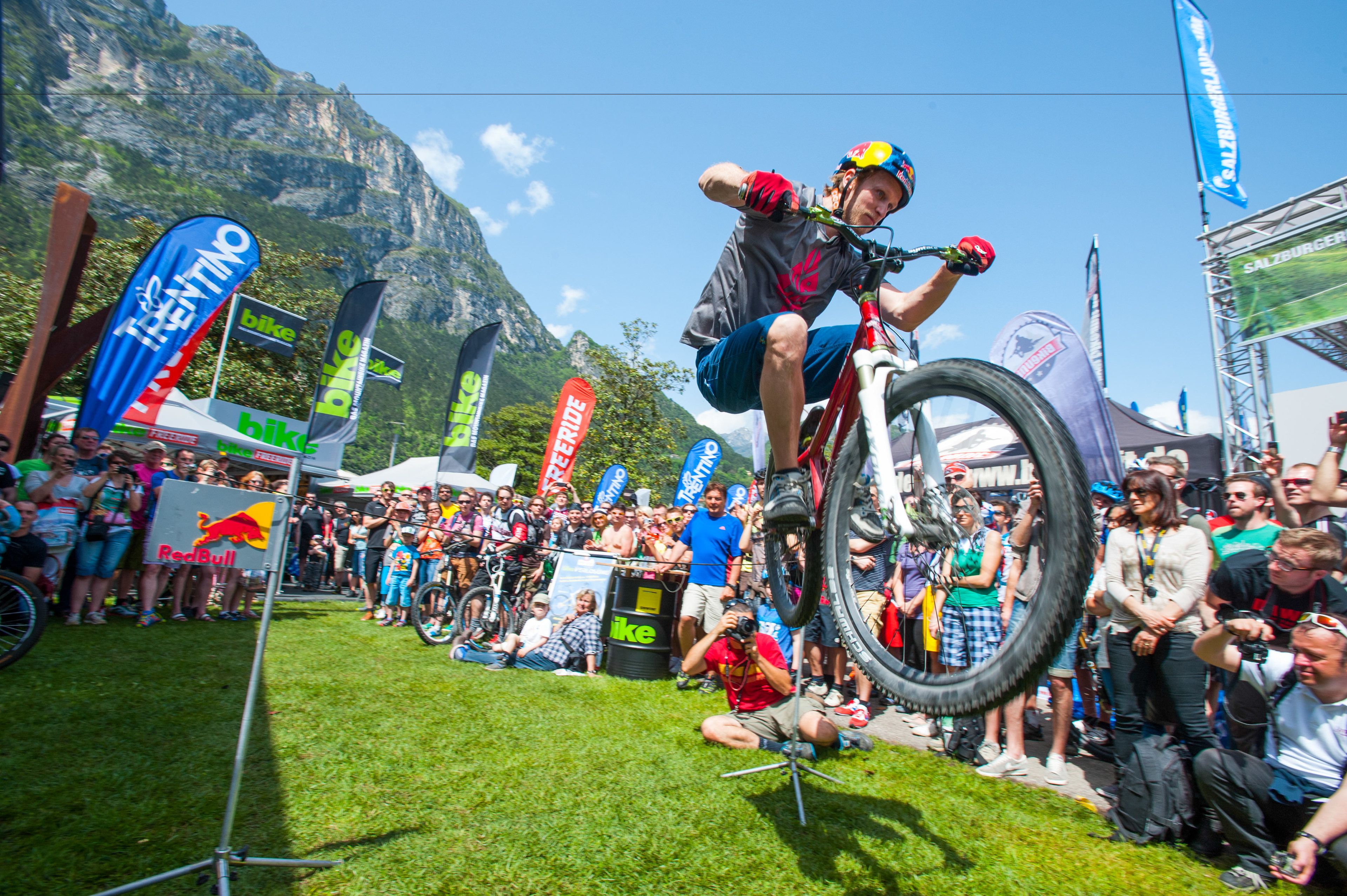 Evento de ciclismo de montaña con una multitud observando a un ciclista realizando una acrobacia.