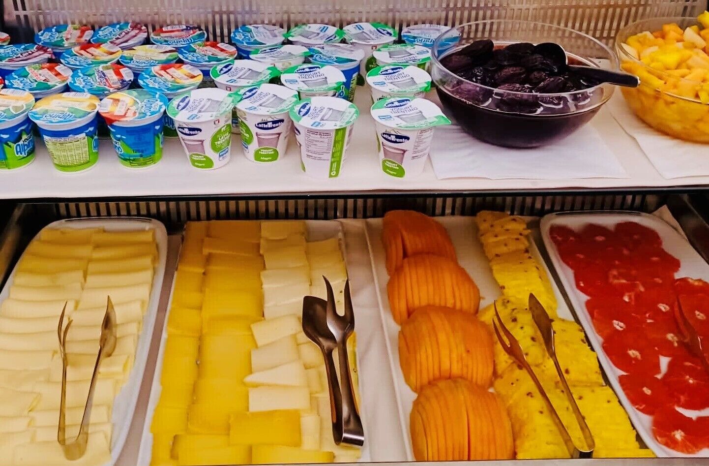 A buffet with various food items including yogurt, fruits, and vegetables.