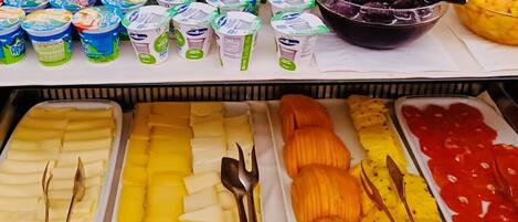 A buffet with various food items including yogurt, fruits, and vegetables.