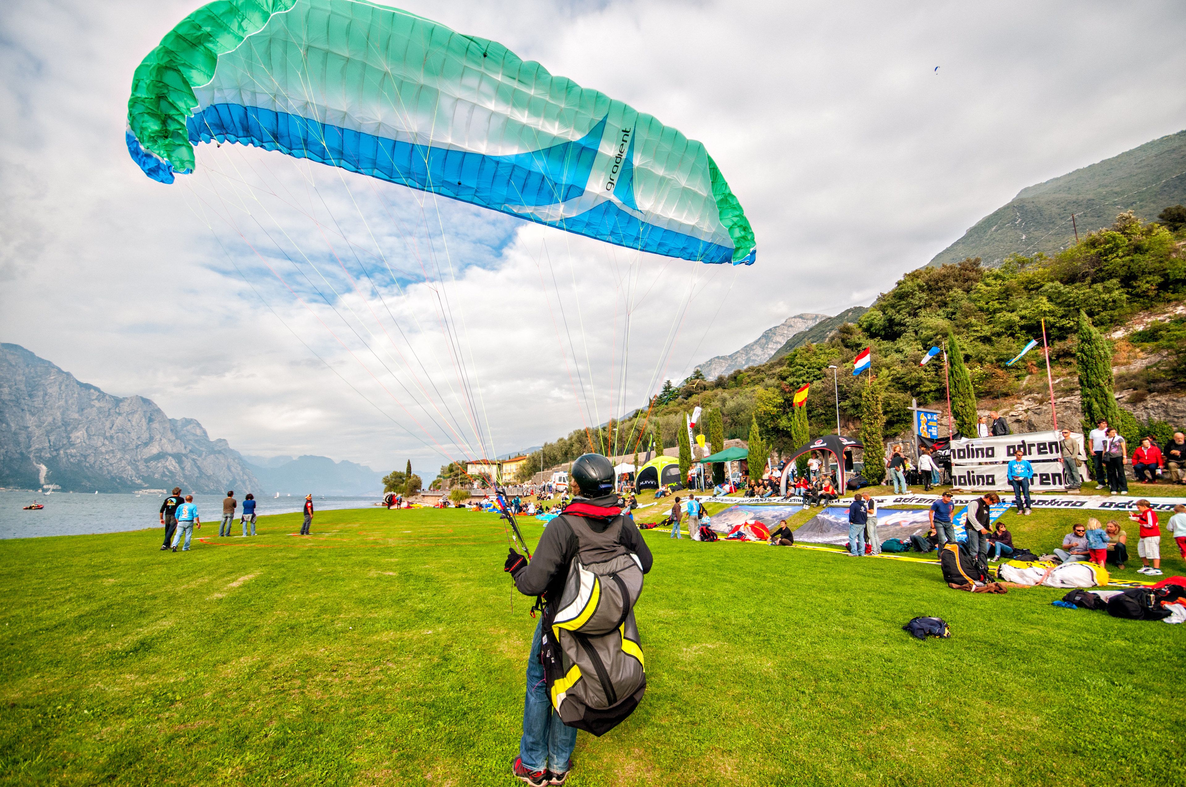 A grassy field with a person preparing to launch a paraglider.