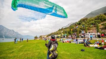 A grassy field with a person preparing to launch a paraglider.