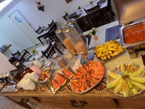 A buffet with various food items including fruits, salads, and condiments. - Hotel Bruggemann (Florianópolis)
