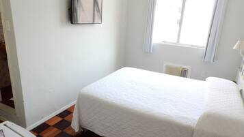 A small, clean room with a bed, a radiator, and a window.