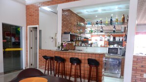 Una cocina moderna con protector mural de ladrillo, una zona de bar con taburetes y una mesa de comedor con individuales.
