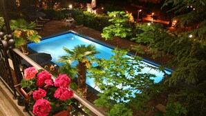 A rectangular pool surrounded by lush greenery and a railing with potted pink flowers. - Miralago (Molveno)