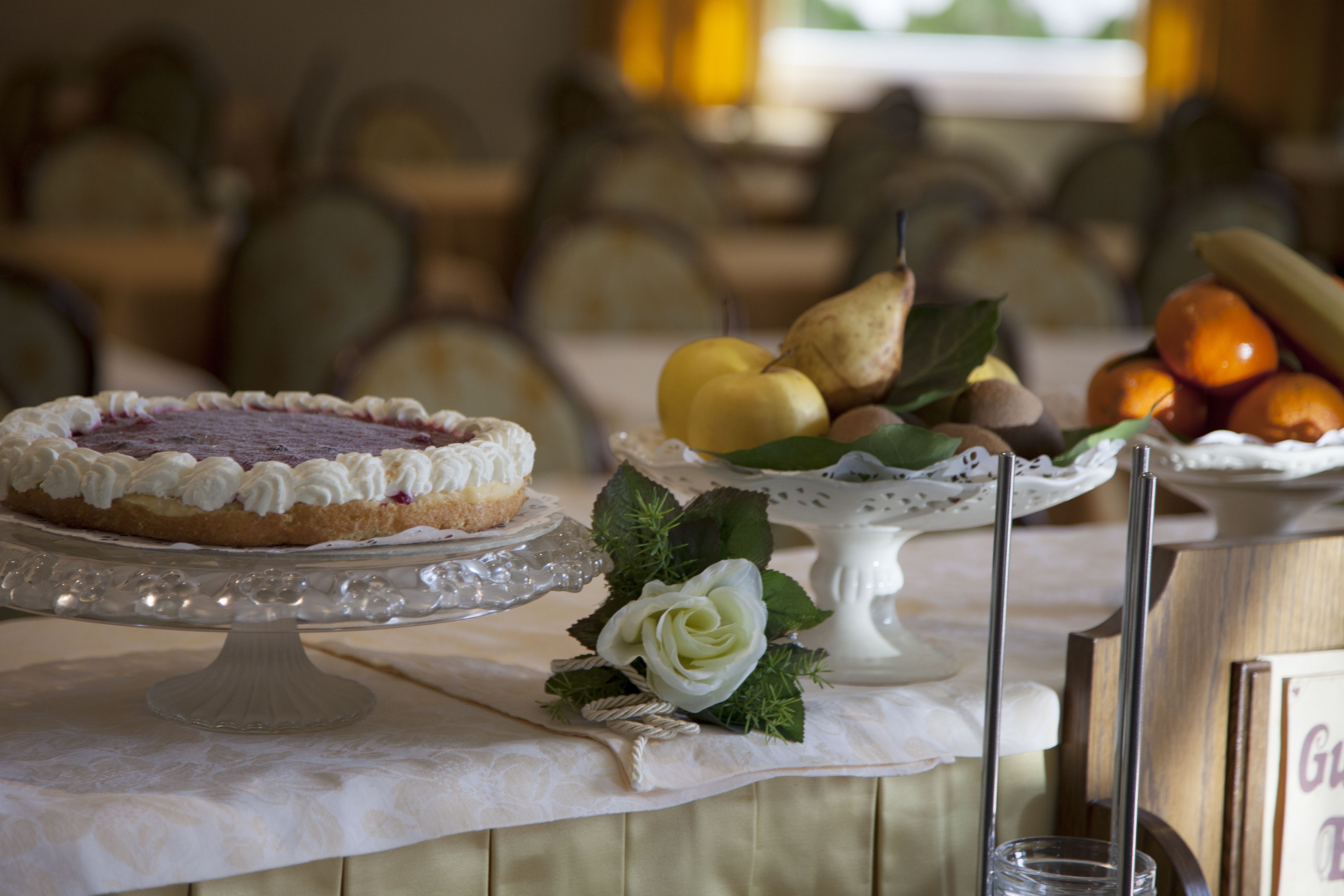 A dessert table with a pie, fruits, and a white flower arrangement.