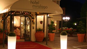 A hotel entrance with a red carpet, potted plants, and a sign reading "hotel miralago". - Miralago (Molveno)