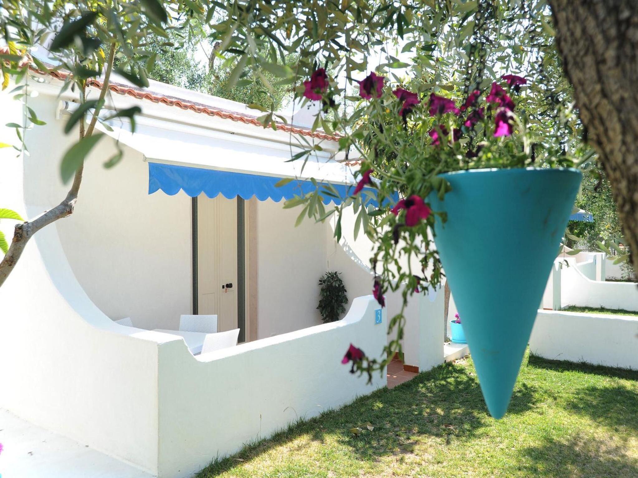 A white building with a blue awning, a door, and a small window.