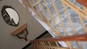 Una escalera de mármol con barandilla de madera y un espejo en la pared.