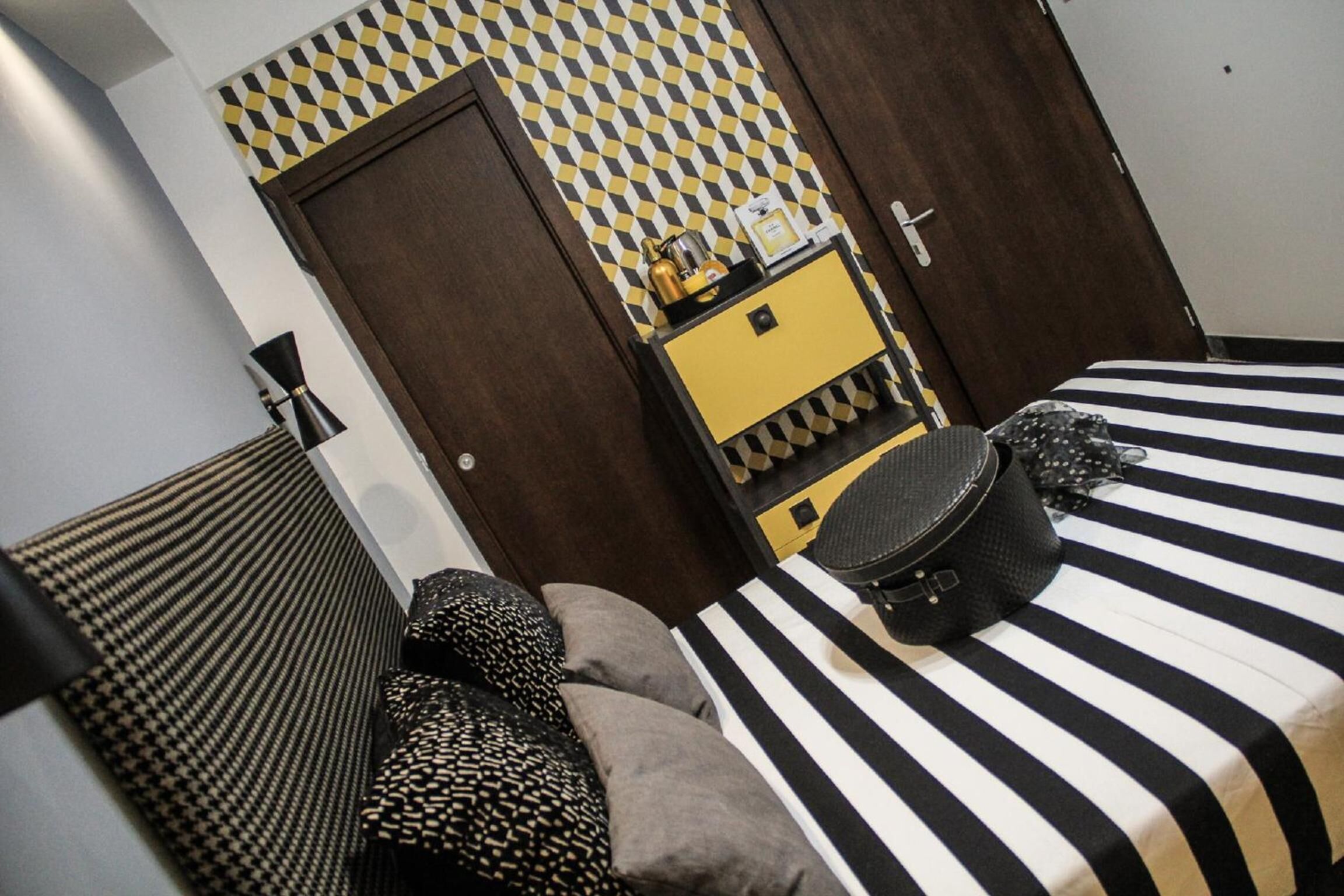 Ein Hotelzimmer mit Bett, Nachttisch, Kommode und einer Wand mit Muster.