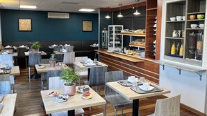 A modern cafe with wooden flooring, multiple seating areas, and a variety of table settings. - Brit Hotel Saumur (Distre)
