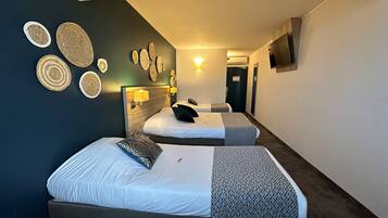 A hotel room with two beds, a TV mounted on the wall, and a hallway leading to another room.