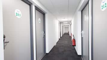 A hallway with doors numbered 211 and 212, carpeted flooring, and a fire extinguisher on the right.