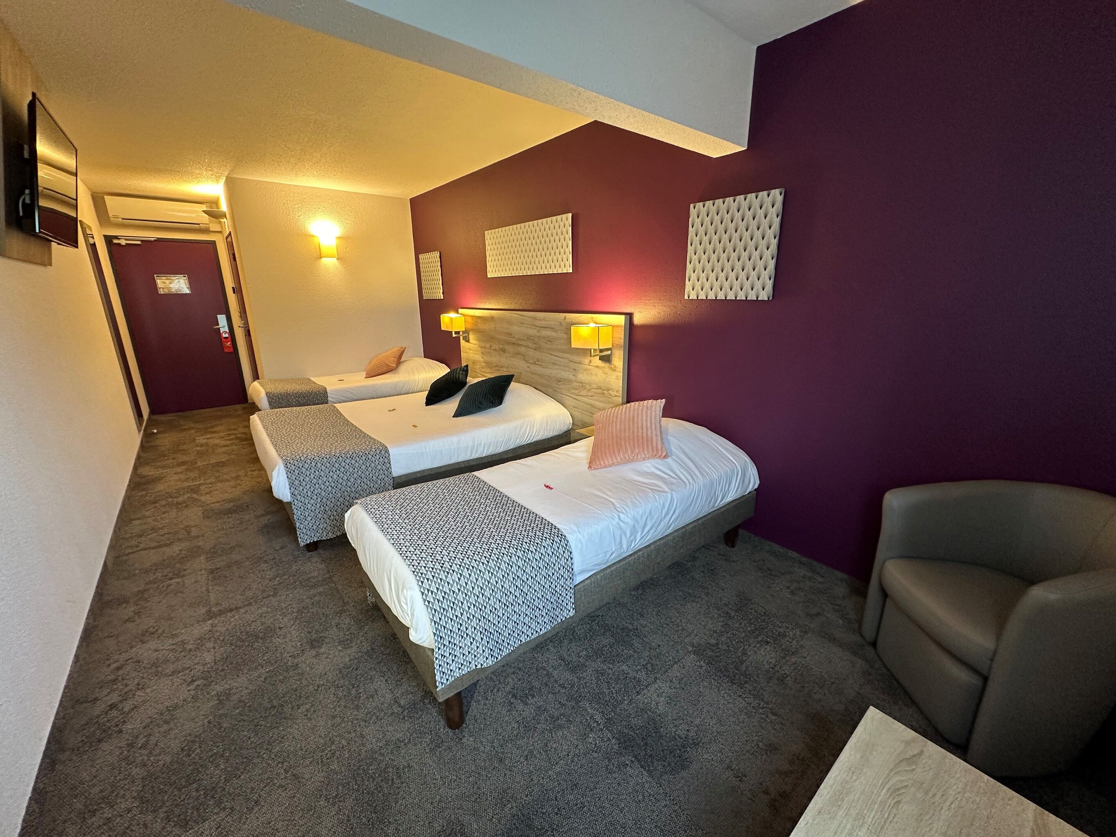 Une chambre d’hôtel avec deux lits, une chaise et une petite table.