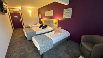 Une chambre d’hôtel avec deux lits, une chaise et une petite table.