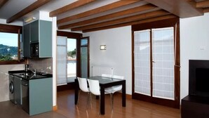 Eine moderne Küche mit Einbauherd, ein Essbereich mit Tisch und Stühlen sowie eine große Glastür, die auf einen Balkon führt.