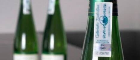 Tres botellas verdes con etiquetas sobre una mesa.