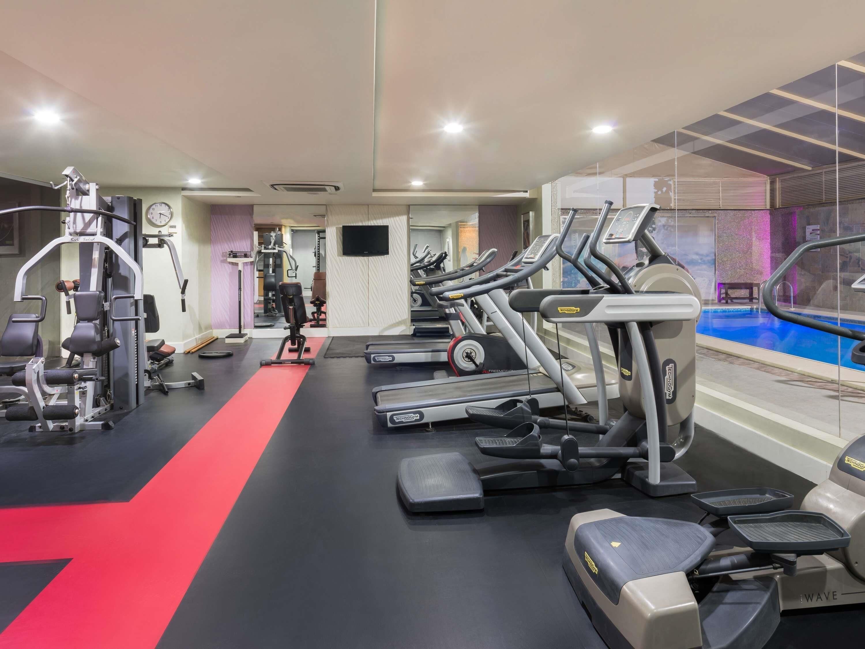 A gym with treadmills, weight machines, and a pool area.