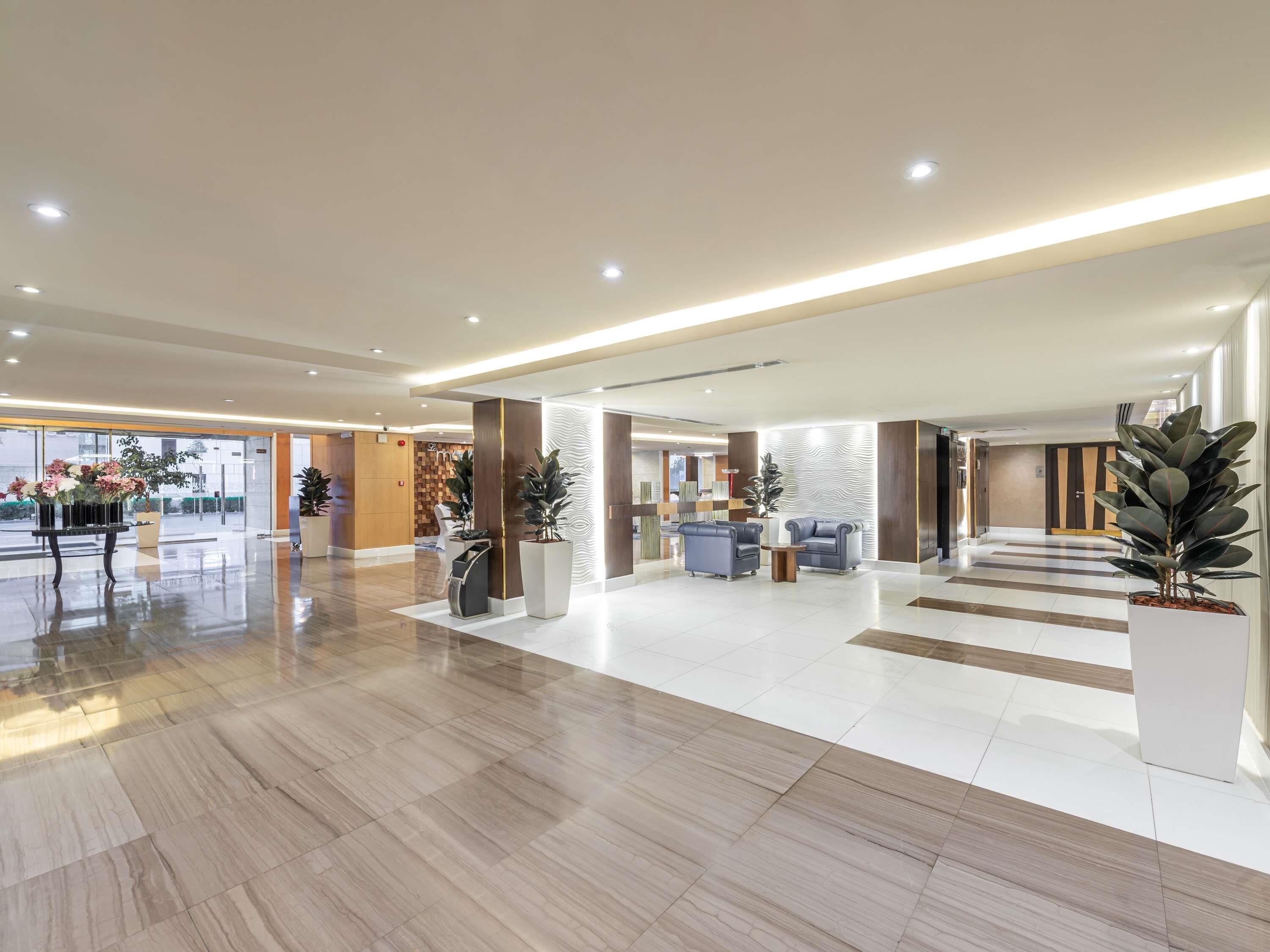 A spacious lobby with a reception desk, seating area, and a large potted plant.
