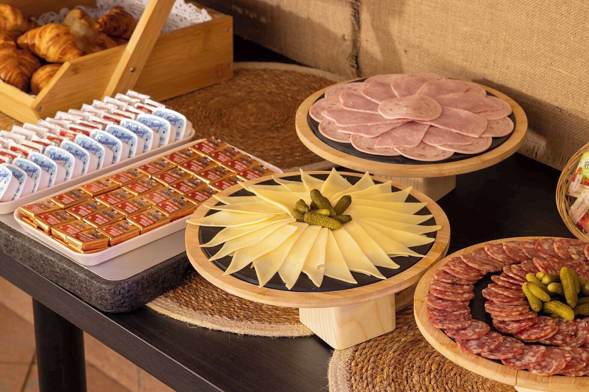 A buffet table with various food items including cheese, ham, and pastries.
