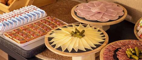 A buffet table with various food items including cheese, ham, and pastries.