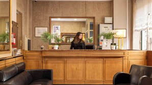 A reception area with a wooden counter, two black leather sofas, and potted plants. - Hotel Saint Pierre (Paris)