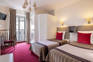 Quarto de hotel com duas camas, uma televisão, uma cadeira e vista para o exterior.