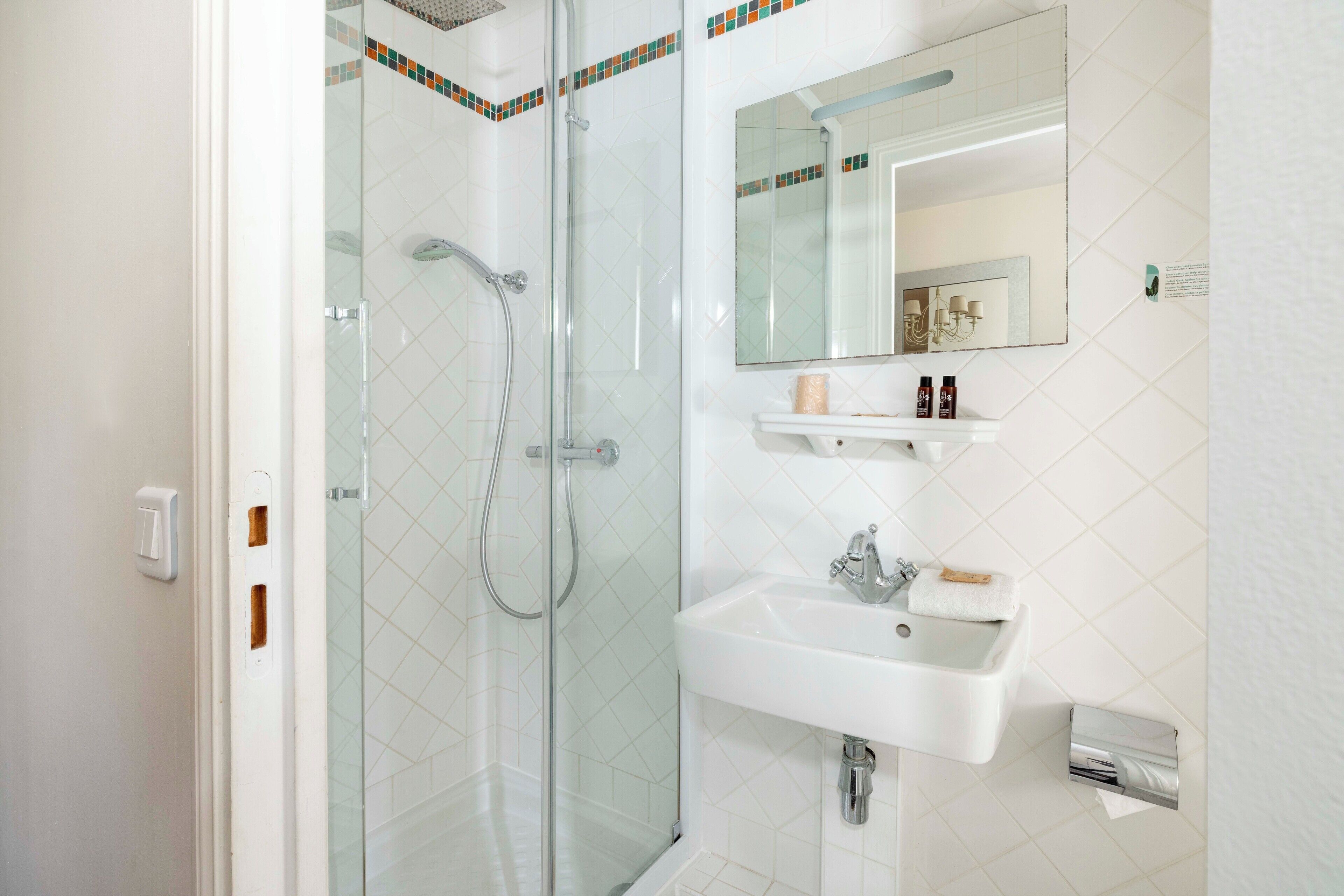 A modern bathroom with a glass-enclosed shower, a white sink, and a mirror above the sink.