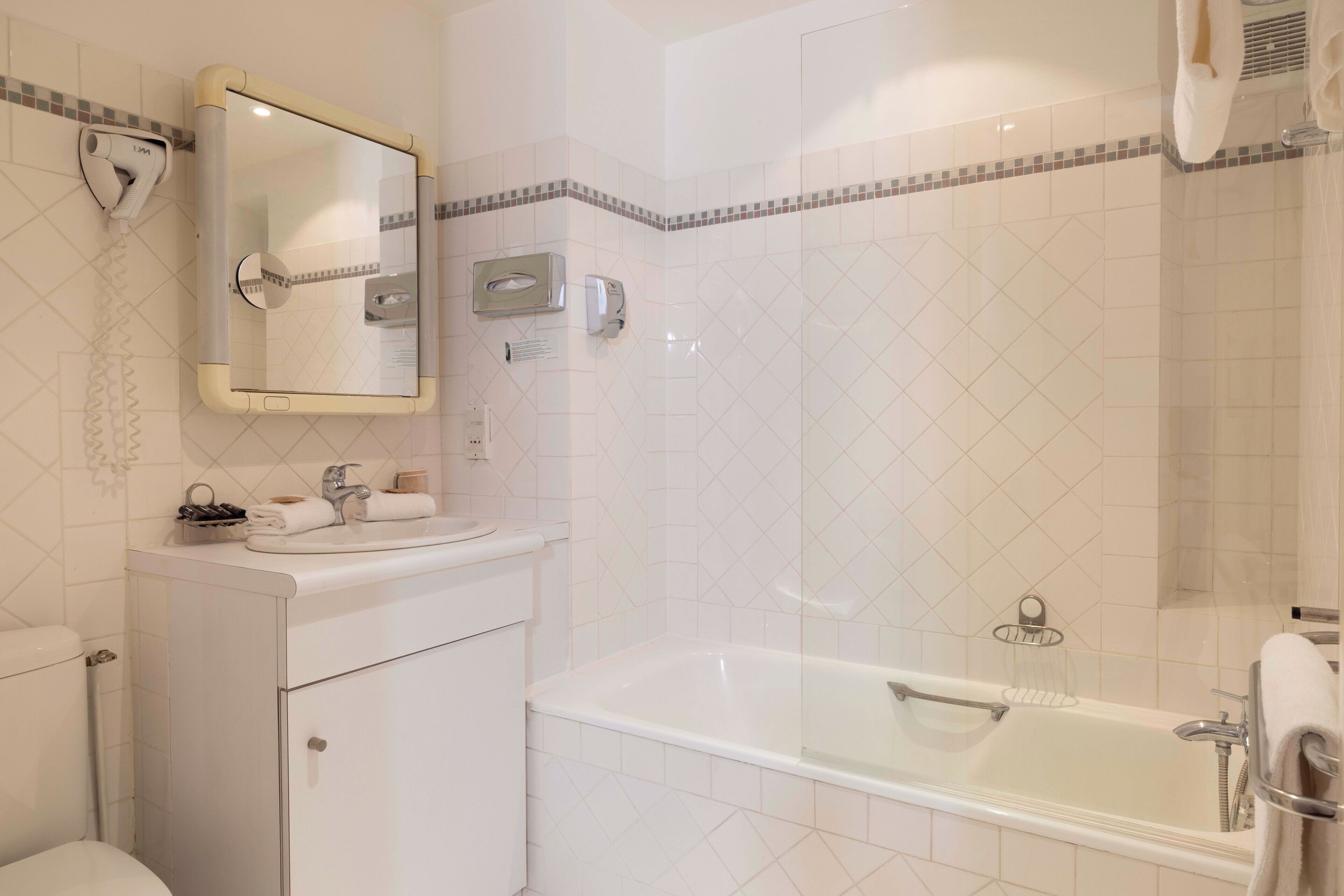Een badkamer met een wit wastafel, spiegel en bad.