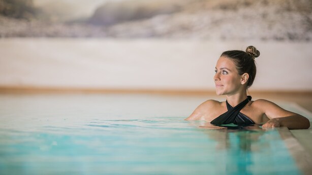Une personne dans une piscine, avec un arrière-plan flou.