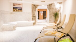 Un espace de détente avec un banc en pierre, une table de massage et une rangée de chaises.