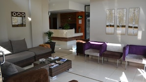 A modern hotel lobby with a reception desk, seating area, and artwork on the walls. - Mesami Hotel (Durban)