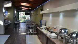A buffet area with a long counter, multiple seating arrangements, and a view of the outdoors. - Mesami Hotel (Durban)