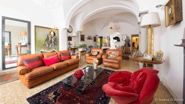 Un salon spacieux avec un canapé en cuir marron, un fauteuil rouge et une table basse.