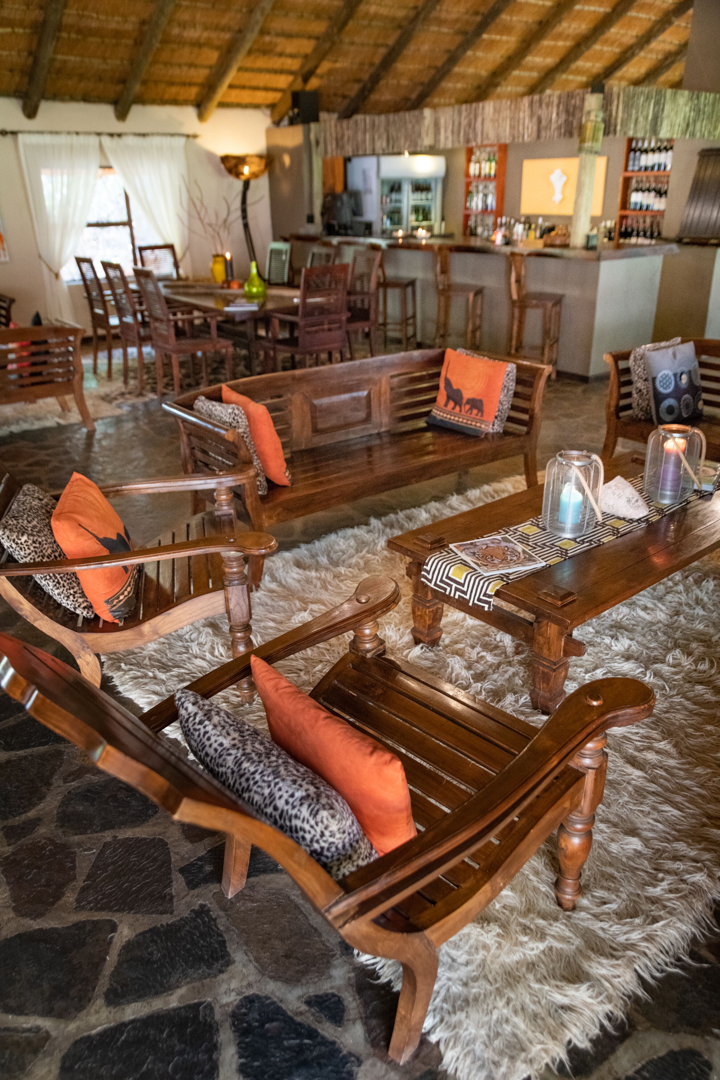 Un rincón tranquilo con muebles de madera, suelo de piedra y un bar al fondo.