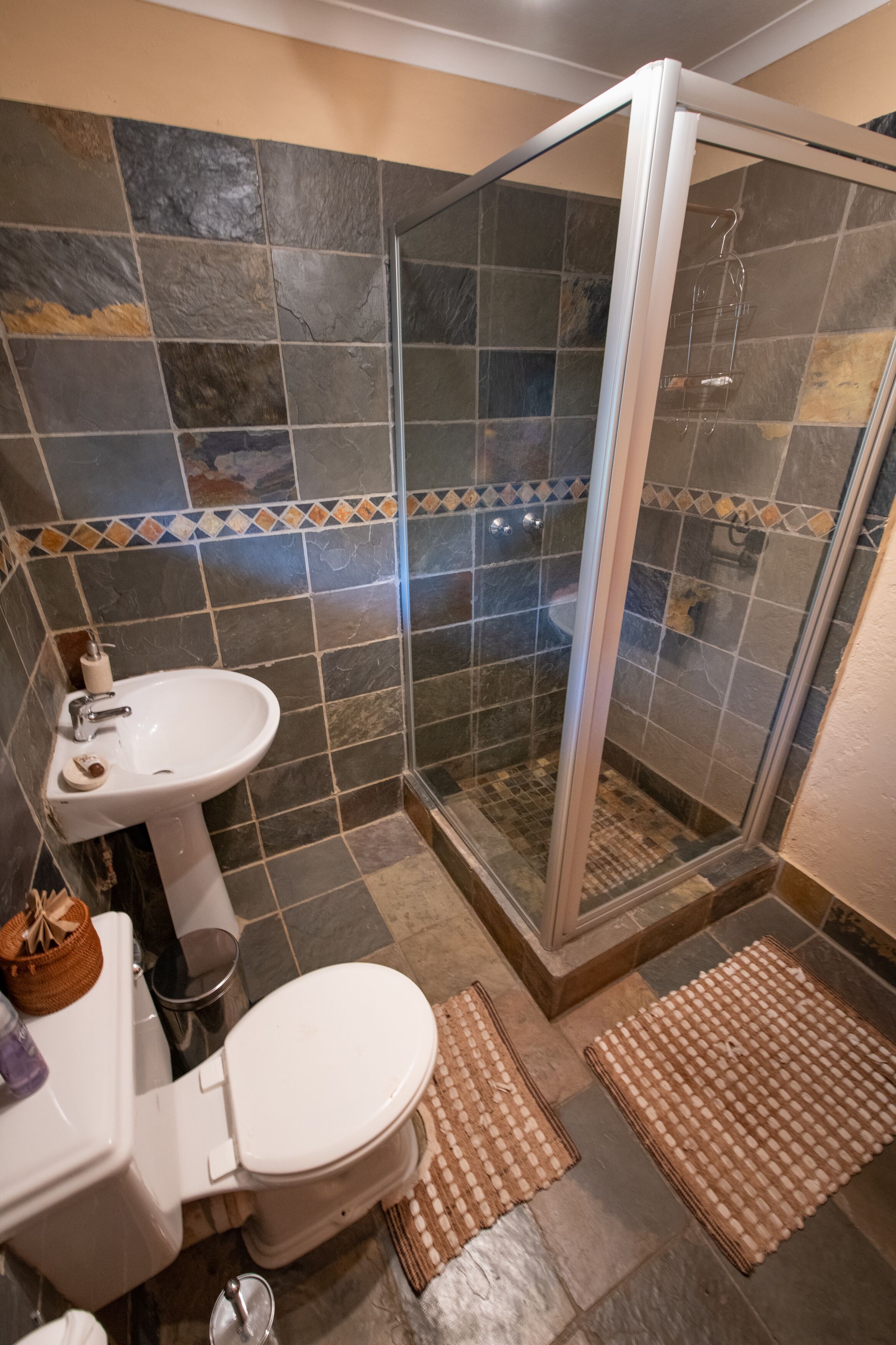 A bathroom with a glass-enclosed shower, a sink, and a toilet.
